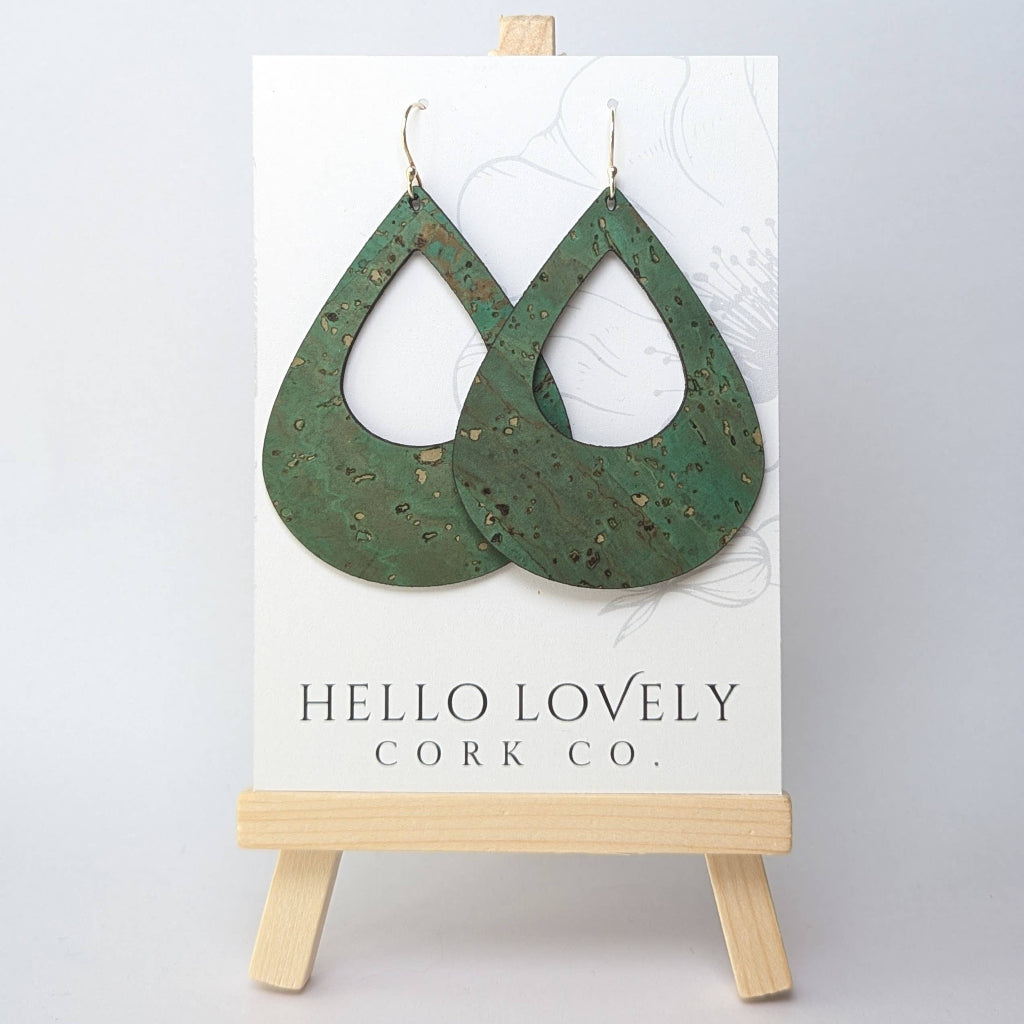 A pair of large teardrop-shaped grass green cork earrings displayed on a white card with the brand name 'Hello Lovely Cork Co.'.