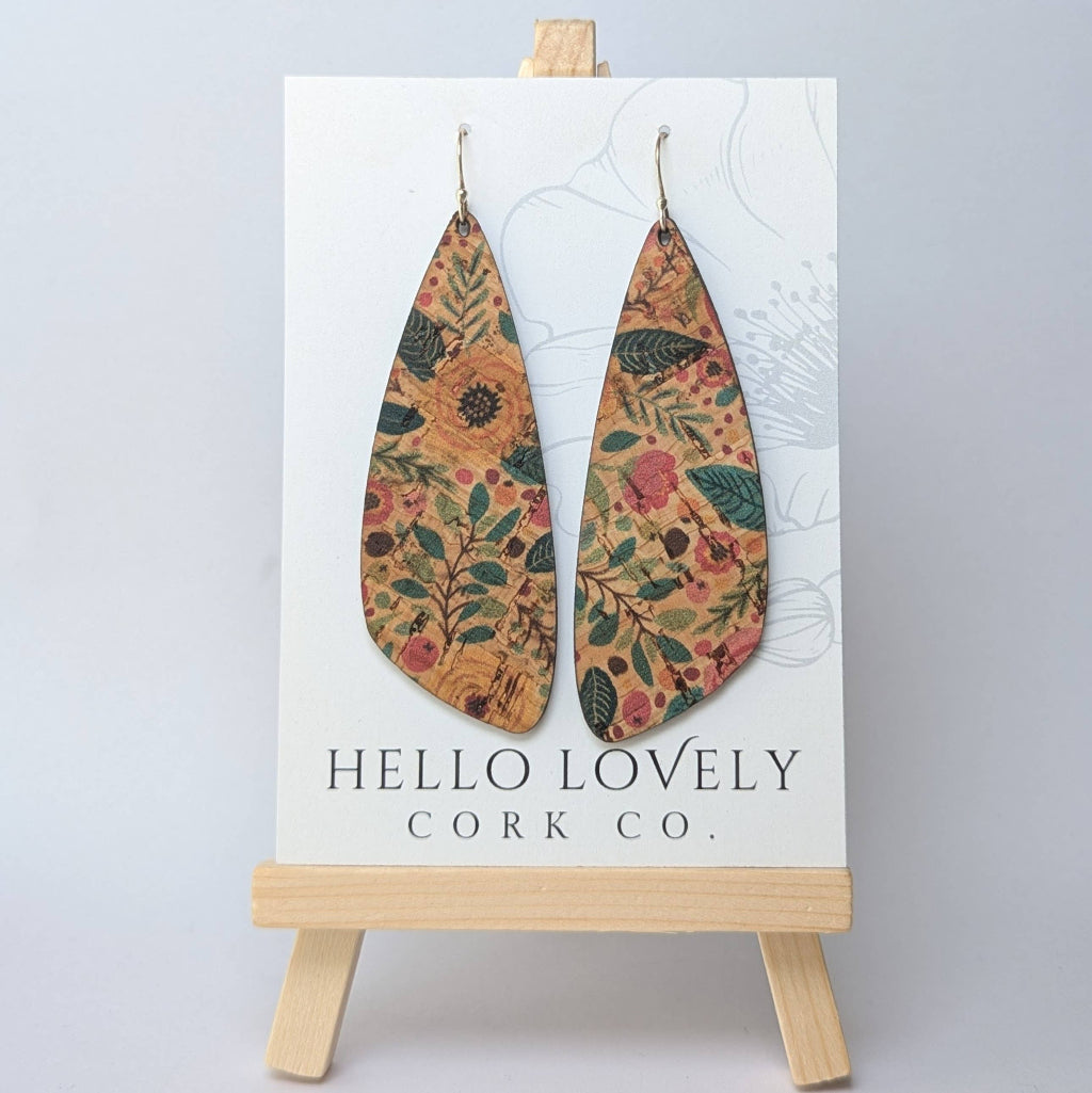 A pair of large, teardrop-shaped, green and pink floral cork earrings displayed on a white card with the text 'HELLO LOVELY Cork Co.'.