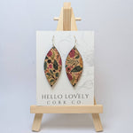A pair of green and pink floral cork earrings displayed on a small wooden easel with the brand name 'Hello Lovely Cork Co.'