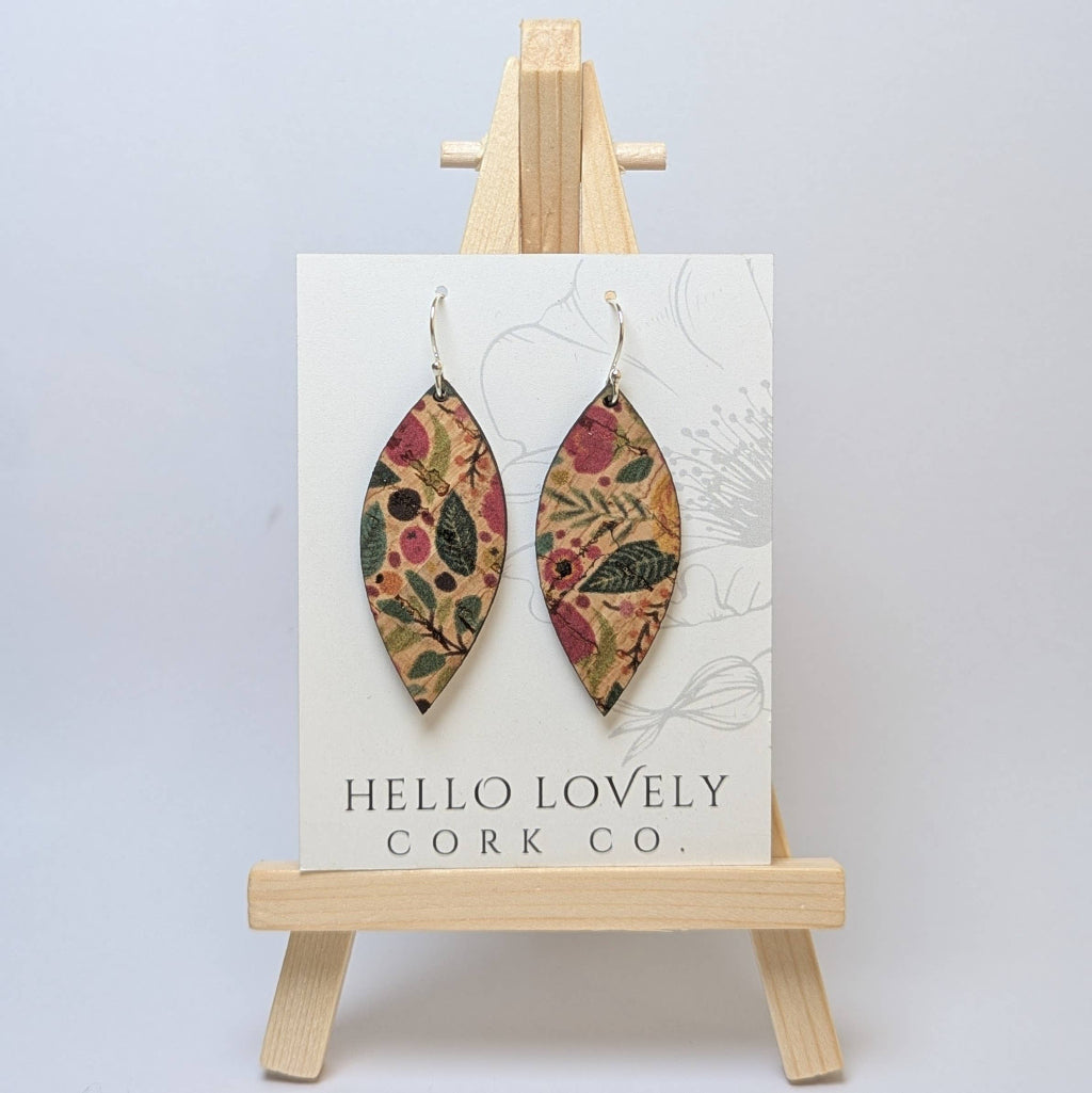 A pair of green and pink floral cork earrings displayed on a small wooden easel with the brand name 'Hello Lovely Cork Co.'