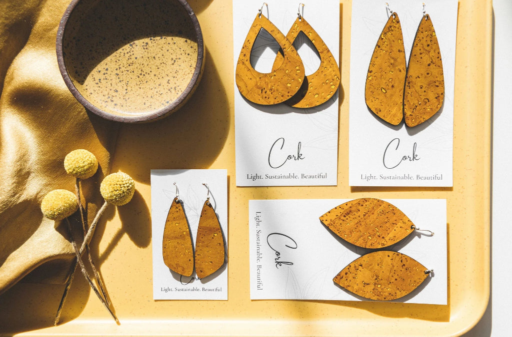 Cork earrings on display with packaging and a bowl on a yellow surface.